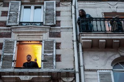 French tenor singer Stephane Senechal, left, sings at his window for the self-isolating inhabitants of his street in Paris, France on March 21, 2020. EPA