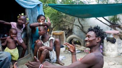 He jokes with a friend as his wife Violene Mareus braids their 9-year-old daughter Changline's hair outside their home near the Truitier landfill. AP Photo