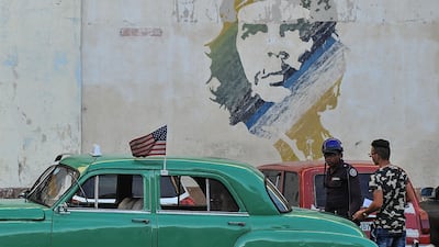 Picture of an old car with a the US flag and a graffiti of revolutionary leader Ernesto 'Che' Guevara.