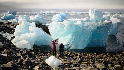 Tourists explore large chunks of ice washed up on the beach in Nuuk, Greenland. Getty Images