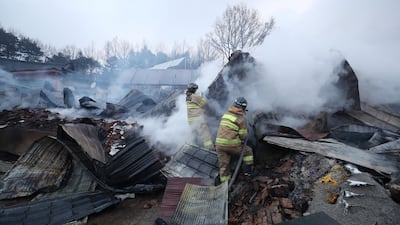 Firefighters put out a fire after a village was swept by the wildfire in Gangneung. Yonhap / Reuters