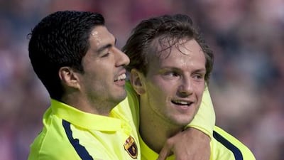 Barcelona’s Croatian midfielder Ivan Rakitic, right, celebrates a goal with Uruguayan forward Luis Suarez during the Spanish Primera Liga match against Granada at the Nuevo Los Carmenes stadium in Granada on February 28, 2015. Jorge Guerrero / AFP