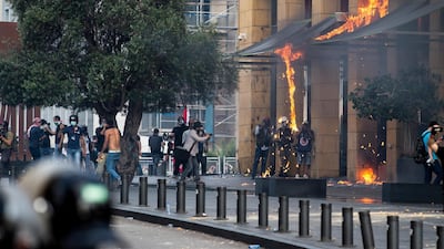 Lebanese security forces watch members of the media taking pictures of flames after a molotov cocktail was thrown by protesters trying to reach the parliament building during clashes with Lebanese riot police at a mass protest against the economic and financial crisis, and to demand early parliamentary elections, in Beirut, Lebanon. EPA