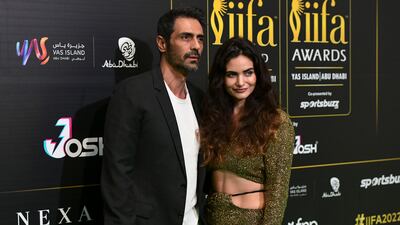 Arjun Rampal in a relaxed blazer over a white T-shirt alongside Gabriella Demetriades, who is wearing a golden two-piece with a cropped top. Khushnum Bhandari / The National