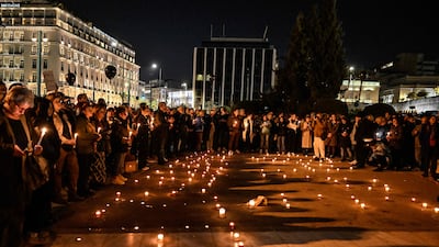 People light candles and hold black balloons during a silent demonstration in front of the parliament in Athens. AFP