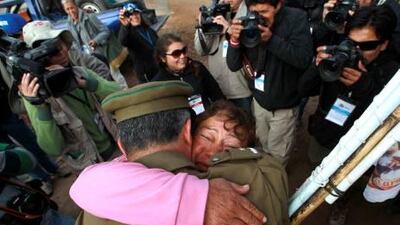 A relative of the 33 miners trapped in the copper and gold mine is hugged by a policeman after the T 130 drilling machine completed an escape hole yesterday.