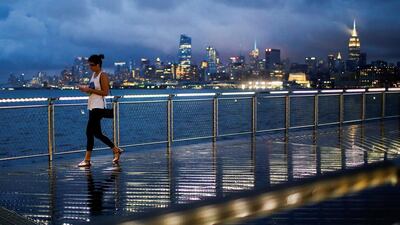 A woman walks on a bridge as low level cloud formation hovers over New York's Empire State Building and the skyline of midtown Manhattan as seen across the Hudson River in Hoboken. Eduardo Munoz / Reuters
