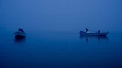 Fisherman cold from the labours of a night out at sea wait in their boats for the Umm Al Qaiwain fish souq to open so they can off load their catch. Antonie Robertson / The National