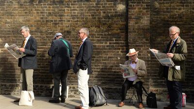 MCC members read newspapers as they wait for the gate to open before the first day. Philip Brown / Reuters / May 21, 2015