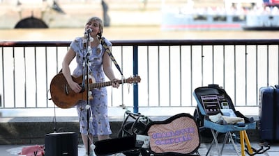 Busker Charlotte Campbell, who uses a contactless card reader for donations in addition to cash, performs near the London Eye in central London. Photo: AFP