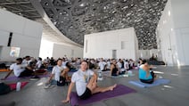 Participants gather under the dome of Louvre Abu Dhabi for a International Day of Yoga celebration. Ryan Lim for The National