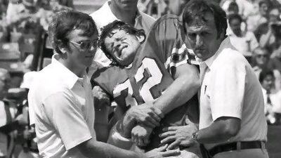 The Atlanta Falcons' Ray Easterling, centre, grimaces while aided by team trainers after getting injured.