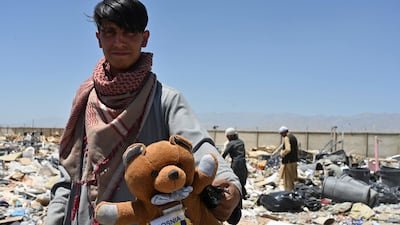 A man holds a teddy bear as people look for useable items at a junkyard near the Bagram Air Base in Bagram. AFP