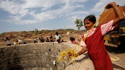 A girl in her school uniform pulls a rope attached to a bucket as she draws water after a tanker emptied water into a dried up well at a village in Maharashtra, India. AP