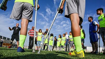 Palestinian child amputees take part in a football training session overseen by Irish coach Simon Baker (L), general secretary of the European Amputee Football Federation, in Deir el-Balah in the central Gaza Strip, on October 18, 2019. - The training is part of an initiative organised by the International Committee of the Red Cross in the Gaza Strip. (Photo by SAID KHATIB / AFP)