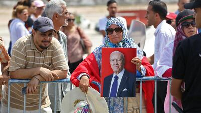 A Tunisian woman carries a portrait of the late president as people gather for the state funeral of late president Essebsi at the El-Jellaz cemetery in Tunis. AFP