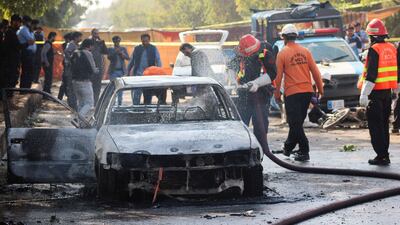 A firefighter douses the wreck of a car with water as forensic officials examine the area outside the court in Islamabad for clues. Reuters