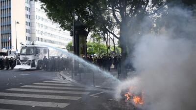 French anti-riot police officers use a water cannon to extinguish a motorbike on fire during clashes with demonstrators on the sidelines of the annual May Day rally in Paris. AFP