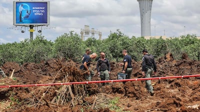 Members of Israeli security services inspect a crater near a road outside the airport. AFP