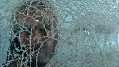 An Afghan bystander is seen through shattered glass at the scene of the September 4 suicide attack on a government compound in Ghazni, during a media tour of the area. Shah Marai / AFP