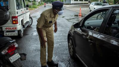 A policeman bends down to check the occupants of a car as he enforces a weekend lockdown to curb the spread of Covid-19 in Kochi, Kerala state, India.