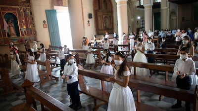 Children wearing protective face masks attend their First Communion ceremony at the Dulce Nombre de Jesus's Catholic church in the Petare neighbourhood of Caracas, Venezuela. AP