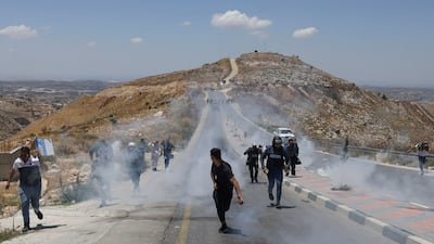 Palestinian landowners, protesters and journalists flee tear gas fired by Israeli security forces during a rally against a new settlement on Mount Tarousa, near Dura, in the Israeli-occupied West Bank. AFP