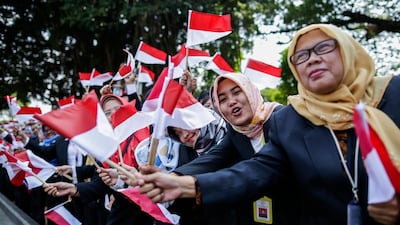 Indonesian presidential palace staff wave national flags as Indonesian President Joko Widodo leaves Merdeka palace for parliament building to be sworn in for his second five-year term. EPA