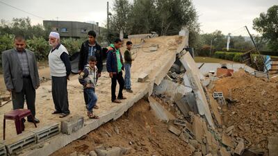 Palestinians stand on the remains of a building. Reuters