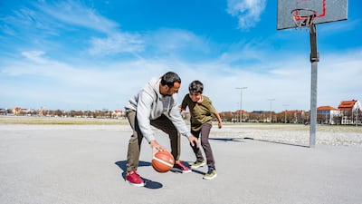 Father and son playing basketball on court outdoors. Getty images