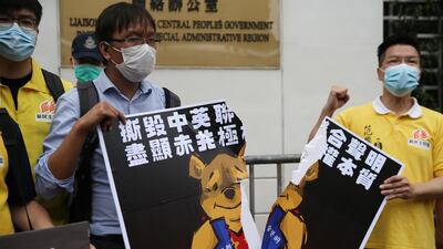 Local district councillors tear a poster, depicting Winnie the Pooh tearing up the 1984 Sino-British Joint Declaration, during a protest against a newly proposed national security law outside the China Liaison Office in Hong Kong, China, 24 May 2020. EPA