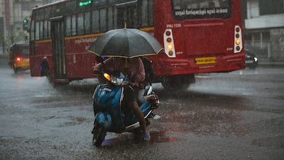 A scooter rider in central Chennai shields himself with an umbrella. EPA