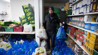 Elyas Ismail, founder of the Newham Community Project food bank, organises food packages ahead of their collection by international students. AFP