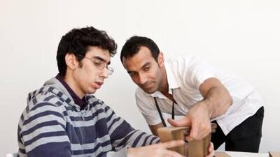 Participant Istanbraq Emad, left, and designer Khalid Shafar, right, build wall art out of cardboard.