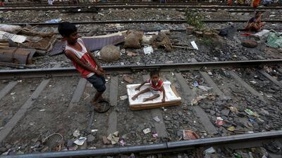 Ratan Mandal, 10, pulls three-year-old Bubai Tati, as he sits on a broken box on a railway track in a slum area.