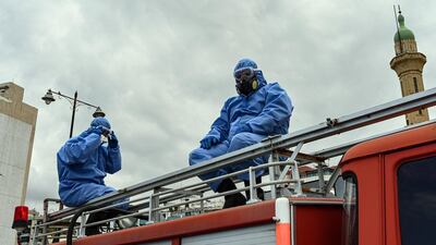 Two municipal workers sit atop a fire truck on Saida’s corniche, preparing to spray the city with disinfectant. The municipality is using protective coveralls made by Mother's Workshop. Finbar Anderson