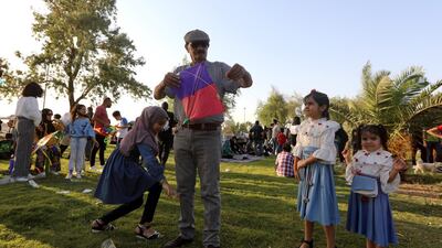 Children watch as a man prepares a kite. EPA