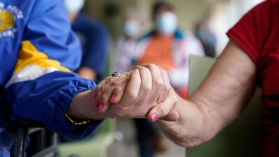 Residents Ken Fishman, 81, left, and Esther Wallach, 82, right, hold hands as they wait in line for the Pfizer-BioNTech vaccine at the The Palace assisted living facility in Coral Gables, Florida, USA. AP Photo