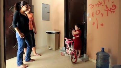 Hiba Saleh, left, stands in front of a wall marked for demolition at Abu Dhabi Gate City.