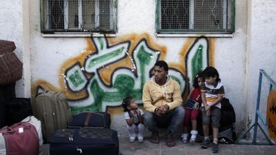 A Palestinian family sit next to their luggage as they wait to enter Egypt through the Rafah border crossing. Khalil Hamra / AP Photo