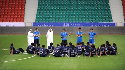 Mahid Ali, the UAE coach, centre, holds a coaching session on the Aspire Academy Stadium pitch in Doha. The air-conditioned facility has allowed the summer tournament to take place.