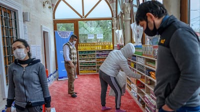People take their need on April 21, 2020, in the Sariyer district of Istanbul, at the entrance of the Dedeman mosque where the racks reserved for shoes of the Muslim faithful is instead loaded with food. AFP
