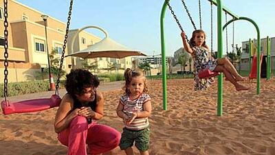 Joanne Rajch plays with her children Gloria and Wiktoria Sinczak, aged one and five, in grounds near their home in Al Reef Villas. “It’s hard to get a flat in the city near a park,” said Mrs Rajch.