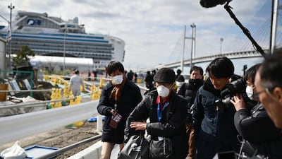 A passenger (C) leaves on foot after dismembarking the Diamond Princess cruise ship (back, L) in quarantine due to fears of the new COVID-19 coronavirus, at the Daikoku Pier Cruise Terminal in Yokohama. AFP
