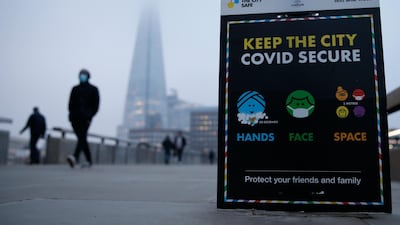 Commuters pass a Covid-19 advice board on London Bridge at sunrise. Getty Images