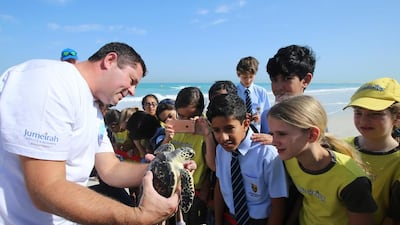 David Robinson, assistant operations manager at Burj Al Arab Aquarium, tells children from Cranleigh School about turtles on Wednesday at Saadiyat Beach Club in Abu Dhabi. Ravindranath K / The National