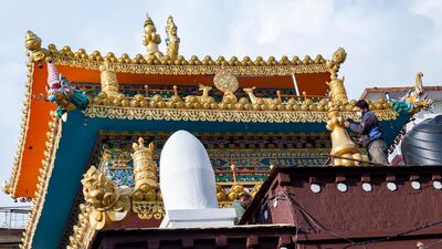A man wearing a mask prepares to paint a stupa of a Tibetan Buddhist temple in Dharmsala, India. AP Photo