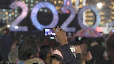 A man takes a picture near the 2020 sign board in the main business district on New Year's Eve in Jakarta, Indonesia. Tens of thousands of revelers in Indonesia's capital of Jakarta were soaked by torrential rains as they waited for New Year's Eve fireworks. AP