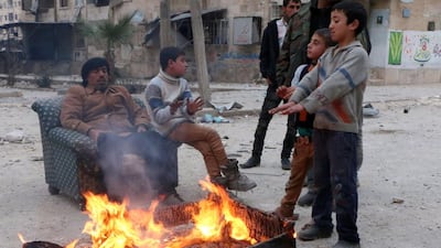 Children warm up with the heat of an armchair burning in the Hanano district of the northern Syrian city of Aleppo on February 15, 2014. The death toll in nearly three years of conflict in Syria has risen to more than 140,000 people including nearly 50,000 civilians, the Syrian Observatory for Human Rights said. Fadi Al-Halabi / AFP photo/Aleppo Media Centre