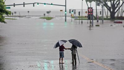 People stand near flood waters in Hilo, Hawaii. Hollyn Johnson / Hawaii Tribune-Herald via AP
